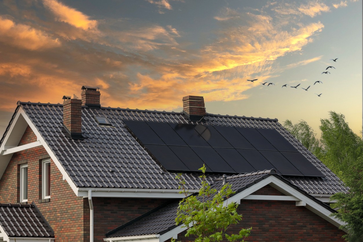 Image d'une maison avec des panneaux photovoltaïques sous un couché de soleil